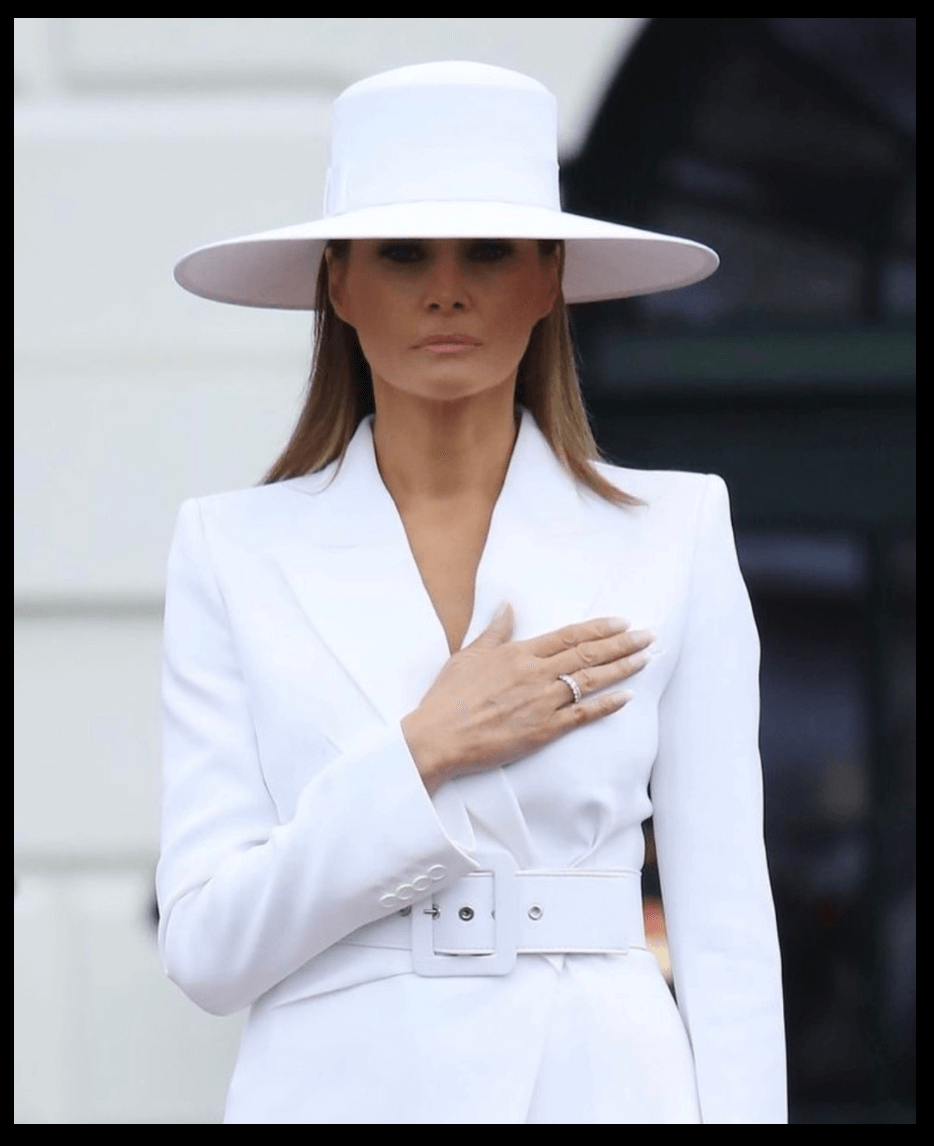 Bílý klobouk se širokou krempou a vysokou korunou, který nosí a podepisuje Melania Trump (Herve Pierre, 2018)